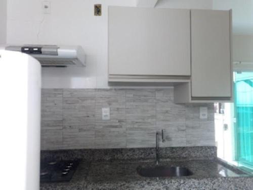 a kitchen with a sink and white cabinets at Flats Nascer do Sol in Cayru