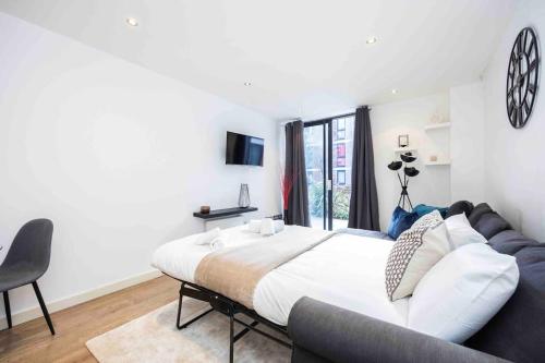um quarto com uma cama grande e um sofá em Stylish 1 BR Apartment Near Shoreditch - 10 Min Walk em Londres