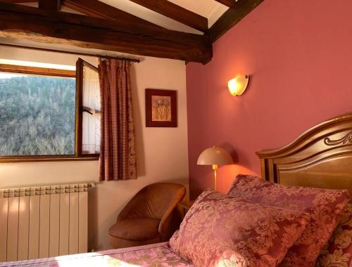 a bedroom with a bed and a chair and a window at Picos de Europa Suites and Rooms in Turieno