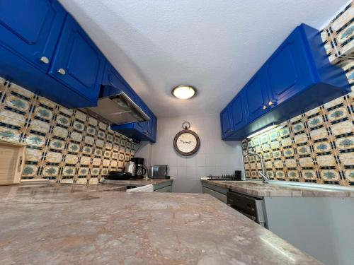 a kitchen with blue cabinets and a clock on the wall at Retro House with Garden in Anopoli in Thessaloniki