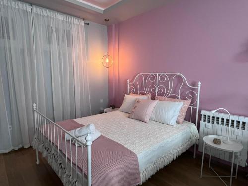 a bedroom with a white bed with pink walls at Retro House with Garden in Anopoli in Thessaloniki