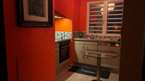 サン・ドニにあるBienvenue chez Maximeのオレンジの壁のキッチン(ガラステーブル付)