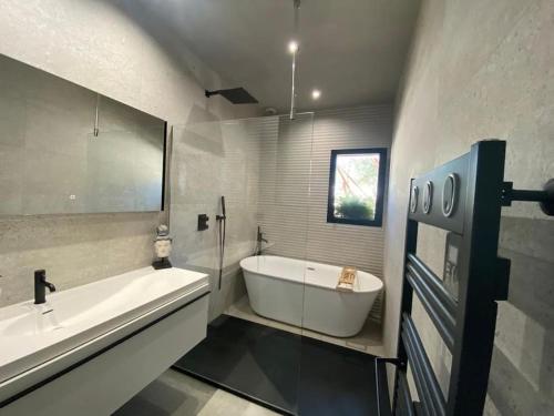 une salle de bain blanche avec une baignoire et un lavabo dans l'établissement La Villa Bali *****, à Nîmes