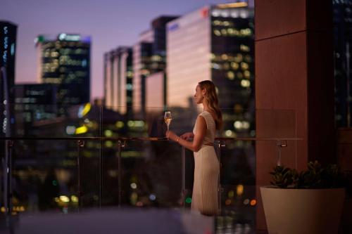 a woman standing on a balcony holding a wine glass at The Ritz-Carlton, Perth in Perth