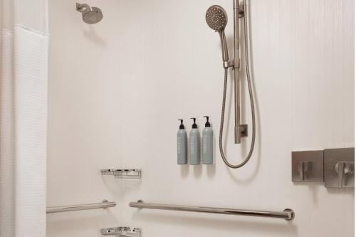 a white bathroom with a shower with bottles on the wall at Courtyard Farmington in Farmington