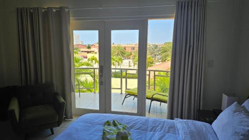 1 dormitorio con cama y vistas a un balcón en Eagle Beach Cozy Condo en Palm-Eagle Beach