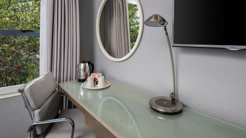 a desk with a lamp and a mirror on it at Holiday Inn Johannesburg OR Tambo Airport Hotel by IHG in Kempton Park