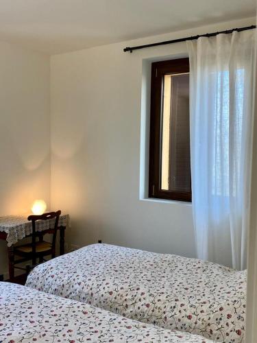 a bedroom with two beds and a window and a table at Villa panoramica sulle colline del Monferrato in Calamandrana