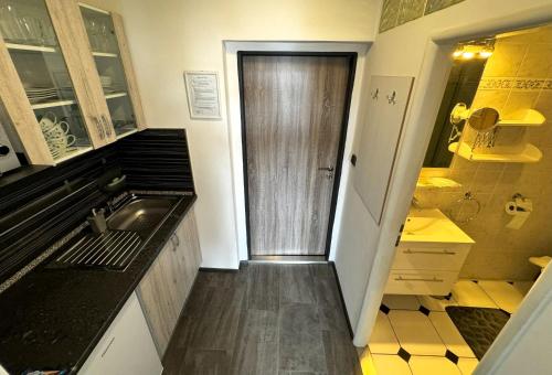 Elle comprend une petite cuisine avec un évier et une porte en bois. dans l'établissement Apartmány Karlovy Vary, à Karlovy Vary