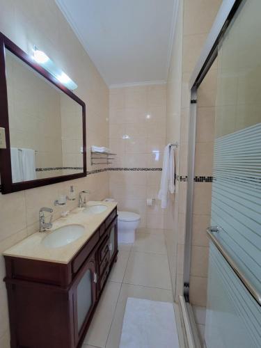 a bathroom with a sink and a toilet and a mirror at Eagle Beach Cozy Condo in Palm-Eagle Beach