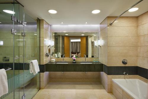La salle de bains est pourvue de 2 lavabos, d'une baignoire et d'un miroir. dans l'établissement Le Meridien Cairo Airport, au Caire