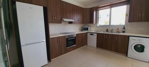 une cuisine avec des placards en bois et un appareil blanc dans l'établissement 3 bedroom Villa in Pyla, à Larnaka