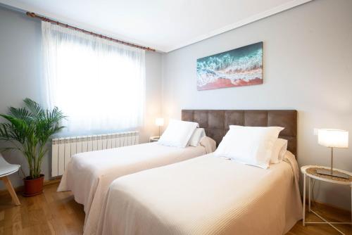 two beds in a room with white sheets at Apartamentos GO - Arroyo San José in Arroyo de la Encomienda