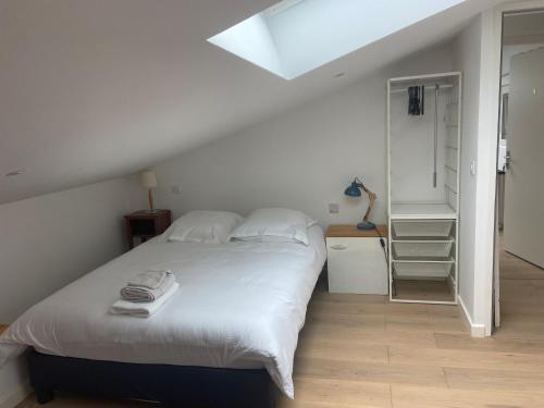 1 dormitorio con cama blanca y tragaluz en Aux portes de Bordeaux, en Mérignac