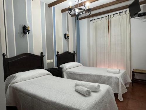 a room with two beds with towels on them at Hostal El Descanso Del Emperador in Jarandilla de la Vera