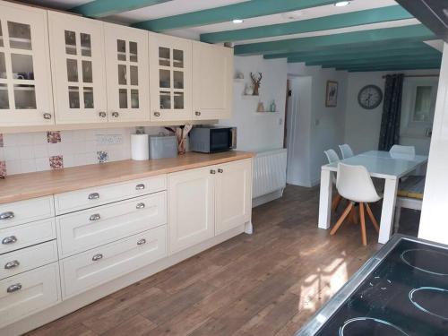 a kitchen with white cabinets and a blue ceiling at Rural Cornish farmhouse in Liskeard