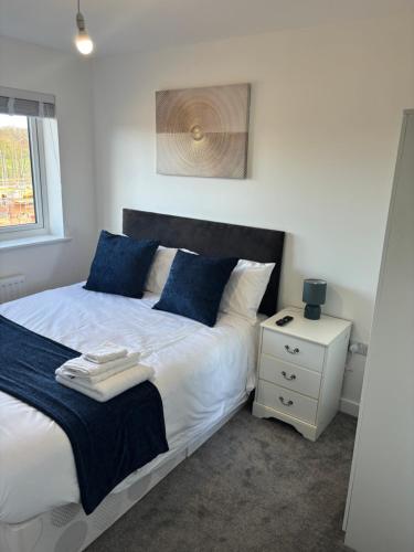 a bedroom with a bed with blue pillows and a night stand at Foxglove Close in Middlesbrough