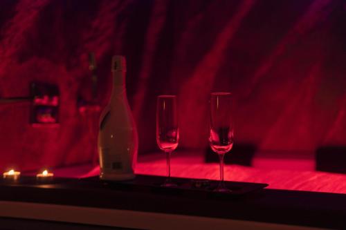 Blue Hole Jacuzzi Suite e B&B Santeramo in Colle في سانتيرامو إن كولي: زجاجة من النبيذ وكأسين من النبيذ على الطاولة