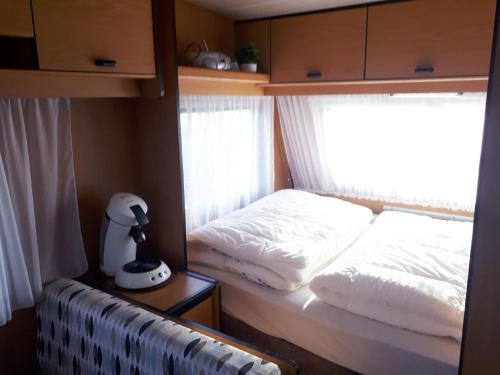 een bed in een kleine kamer met een raam bij Mobilheim für 2 Personen ca 10 qm in Buren, Friesland Ameland in Buren