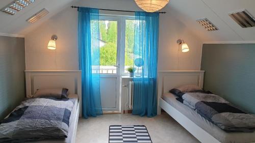 1 dormitorio con 2 camas y una ventana con cortinas azules en Villa Norrland, modern im skandinavischen Stil, mit Kamin, Garten und Saunafass, en Vidsel