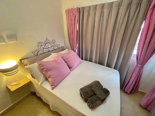 ein kleines Schlafzimmer mit einem Bett mit rosa Kissen in der Unterkunft Apartamento con terraza & BBQ in Mendoza