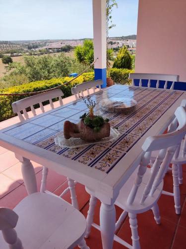 a table with white chairs and a table with a plant on it at Cerca da Ponte in Almodôvar