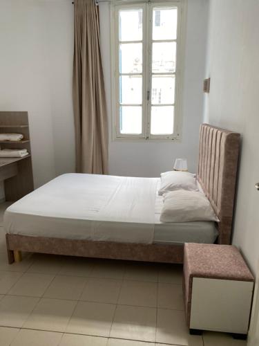 a bed in a room with a window and a chair at Appartement de ville in Tunis