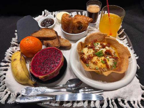 a breakfast tray with a plate of breakfast foods and drinks at Studio Cosy KAZADALO, Deux Rives - Sainte-Suzanne in Sainte-Suzanne
