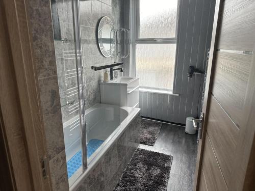 a bathroom with a tub and a sink and a mirror at Impeccable 3-Bed House in Great Yarmouth in Great Yarmouth