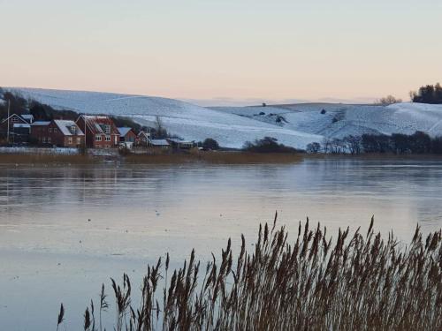 a snow covered field with houses and a lake at Haus Fabjerg in Lemvig