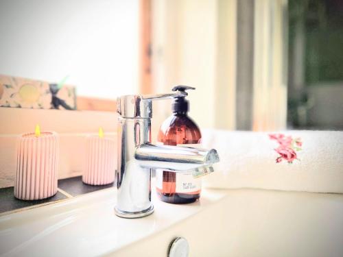 un dispenser di sapone seduto su un lavandino accanto alle candele di Haus Fabjerg a Lemvig