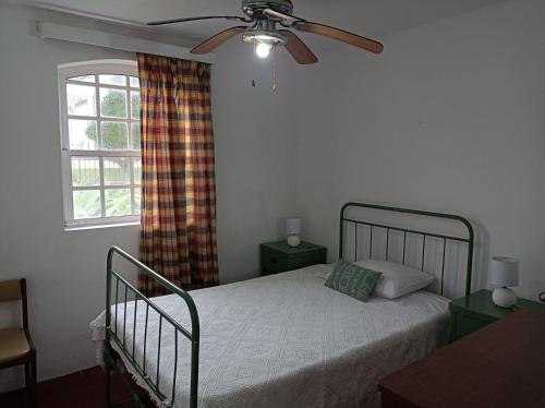 a bedroom with a bed with a ceiling fan and a window at Rosário Guest House in Lajes