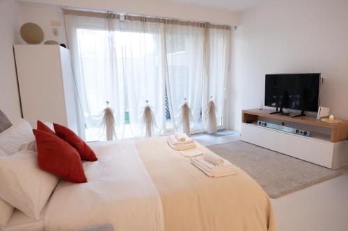 a white bedroom with a large bed and a television at GINNY HOUSE VENEZIA in Dolo
