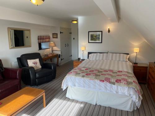 a bedroom with a bed and a chair and a desk at The Cruck Barn, cosy rural escape near The Peak District in Matlock