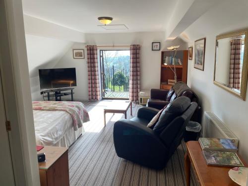 a living room with a couch and a bed and a television at The Cruck Barn, cosy rural escape near The Peak District in Matlock