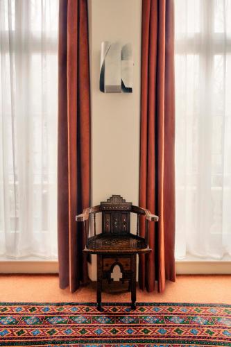 a chair sitting on a rug in a room with curtains at Grand Hotel Bellevue London in London