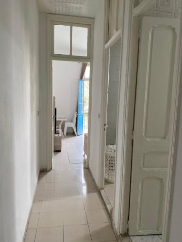 a hallway with a white door and a mirror at Appartement de ville in Tunis