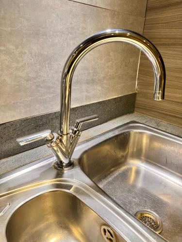 a stainless steel sink with a faucet in a kitchen at Luxury rooms in canary wharf in London