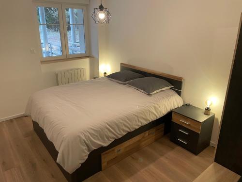 um quarto com uma cama e uma mesa de cabeceira com 2 candeeiros em Appartement - Au cœur du Lac Blanc em Orbey