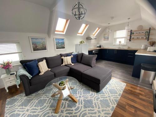 Una sala de estar con un sofá y una cocina. en The Penthouse at Percy House Pet Friendly 2 Bedroom Apartment in Porthcawl Sleeps 4 people Located in the town centre, en Porthcawl