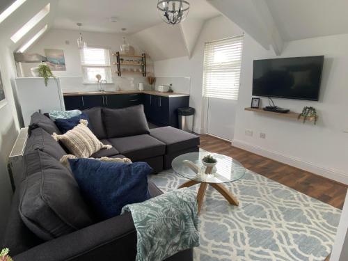 a living room with a couch and a tv at The Penthouse at Percy House Pet Friendly 2 Bedroom Apartment in Porthcawl Sleeps 4 people Located in the town centre in Porthcawl