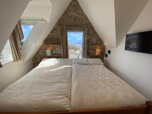 a bedroom with a large bed in a attic at THE PENTHOUSE APARTMENT with an 18ft by 14ft balcony with amazing VIEWS over ST IVES HARBOUR and BAY perfect from Alfresco dining and sunbathing, ONSITE PARKING, LARGER GROUPS book our connecting apartments in St Ives