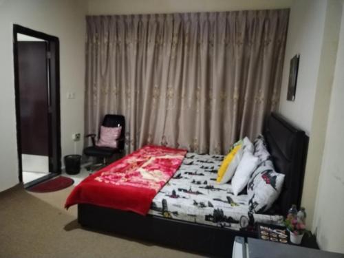 un dormitorio con una cama y una silla en My Home Stay Apartment, en Abu Dabi