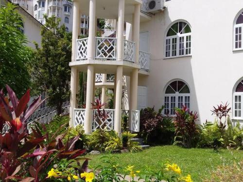 a white house with a balcony in the yard at Refreshed Modern Country Feel Apartment in Ocho Rios