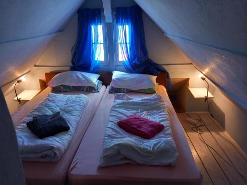 two beds in a small room with blue curtains at Hexen Haus in Burghaslach