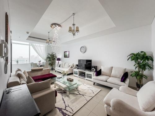 a living room with white furniture and a chandelier at 2-BDR, Dubai Marina, Canal and city view in Dubai