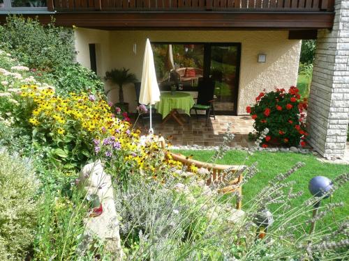 a garden with flowers and an umbrella on a house at Ferienwohnung Klaus in Ebermannstadt