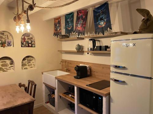 een keuken met een witte koelkast en een tafel bij Impasse des Mystères - La maison des Sorciers Léhon/Dinan in Dinan
