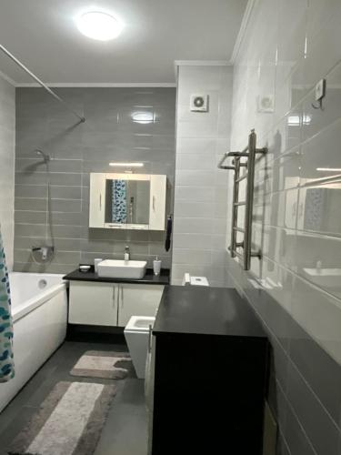 een badkamer met een wastafel, een toilet en een bad bij Просторная современная 2-комнатная квартира in Alma-Ata