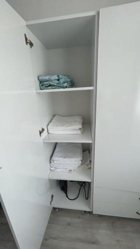 a white closet with white shelves and towels at Backyard Apart in Kemer